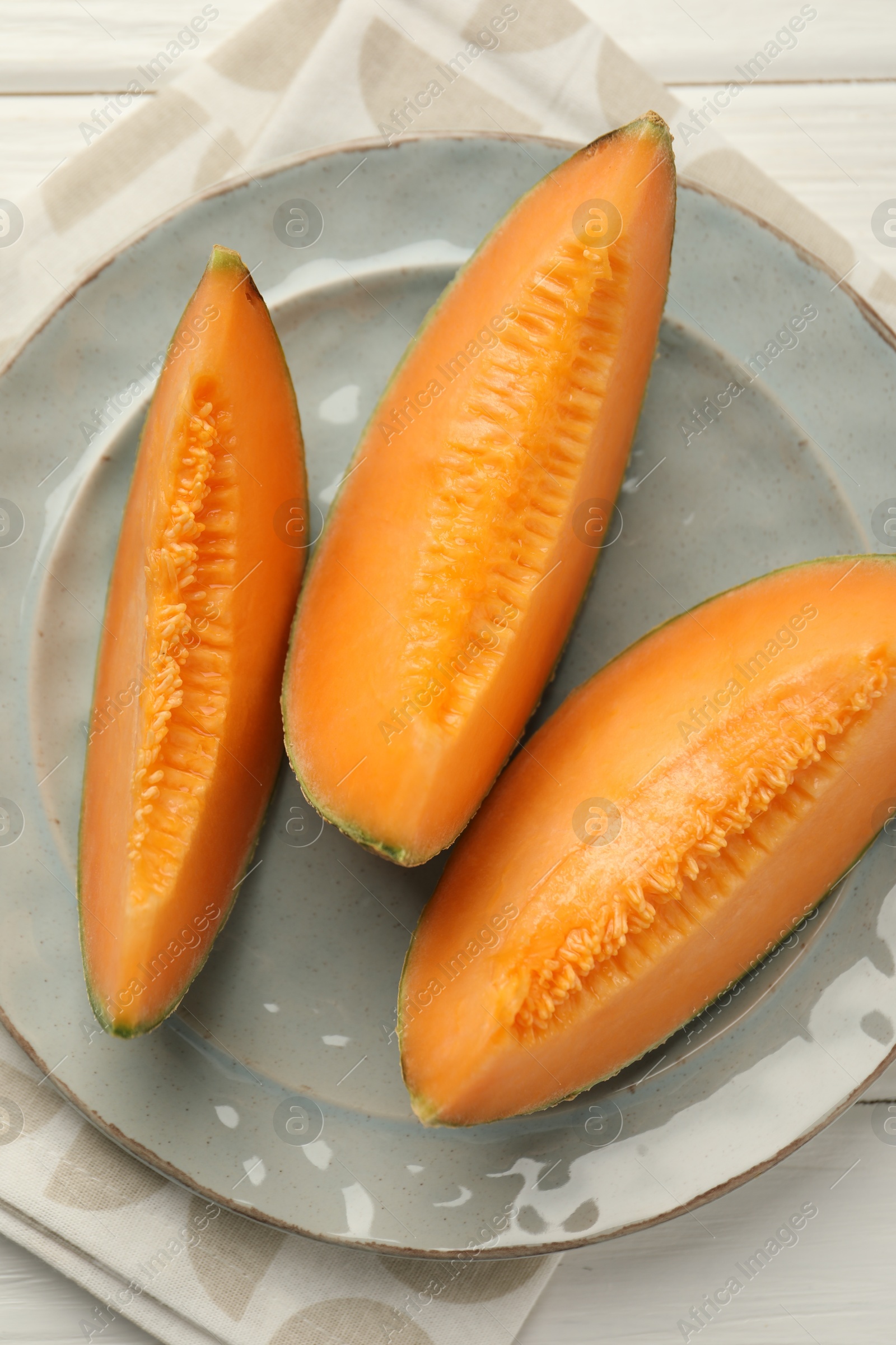 Photo of Pieces of fresh Cantaloupe melon on white wooden table, top view