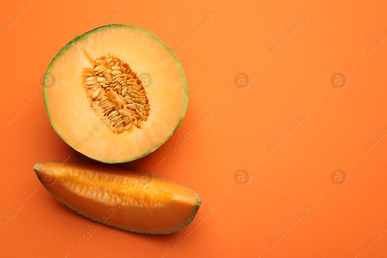 Photo of Pieces of fresh Cantaloupe melon on orange table, flat lay. Space for text