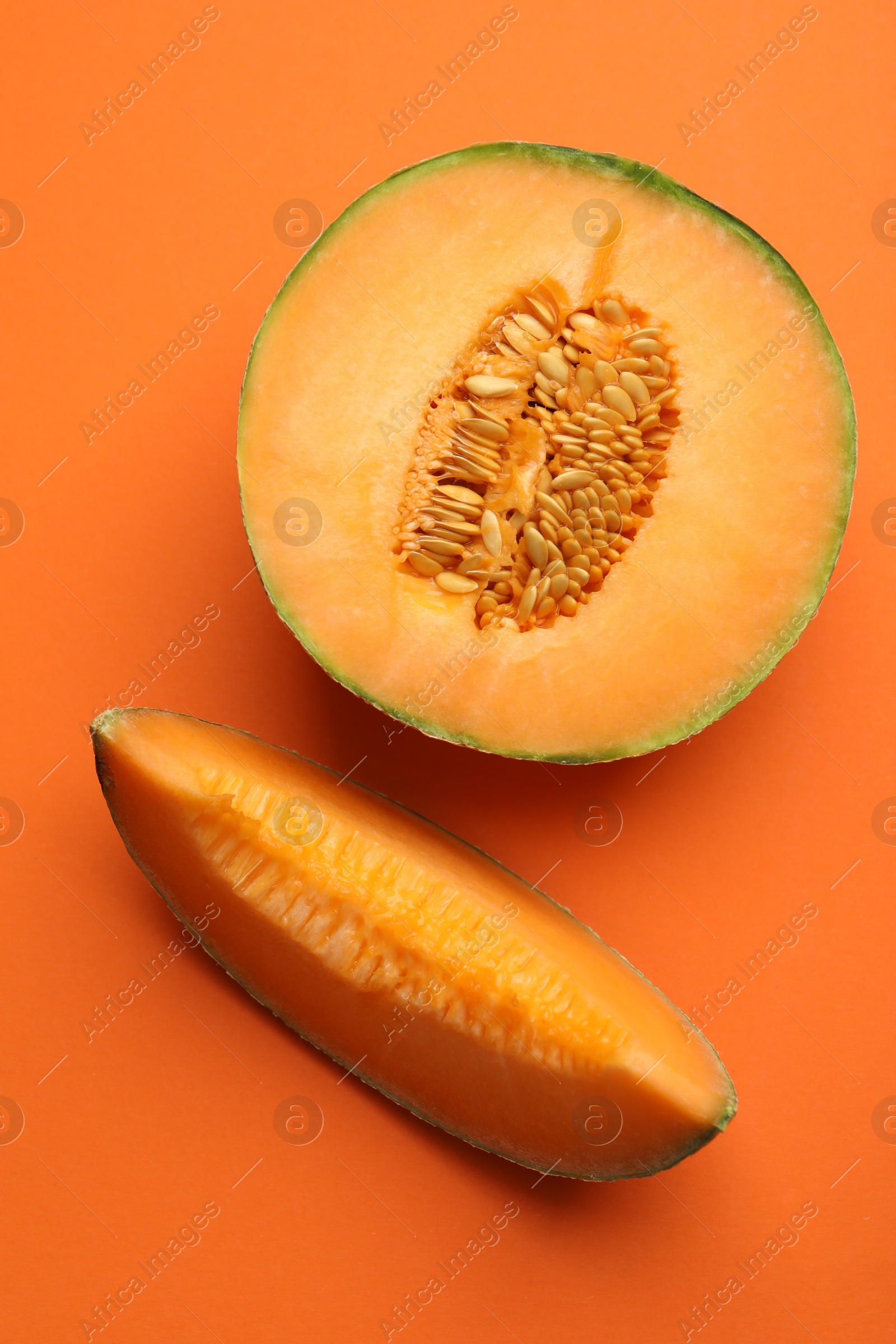 Photo of Pieces of fresh Cantaloupe melon on orange table, flat lay