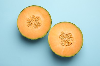 Halves of fresh Cantaloupe melon on light blue table, flat lay