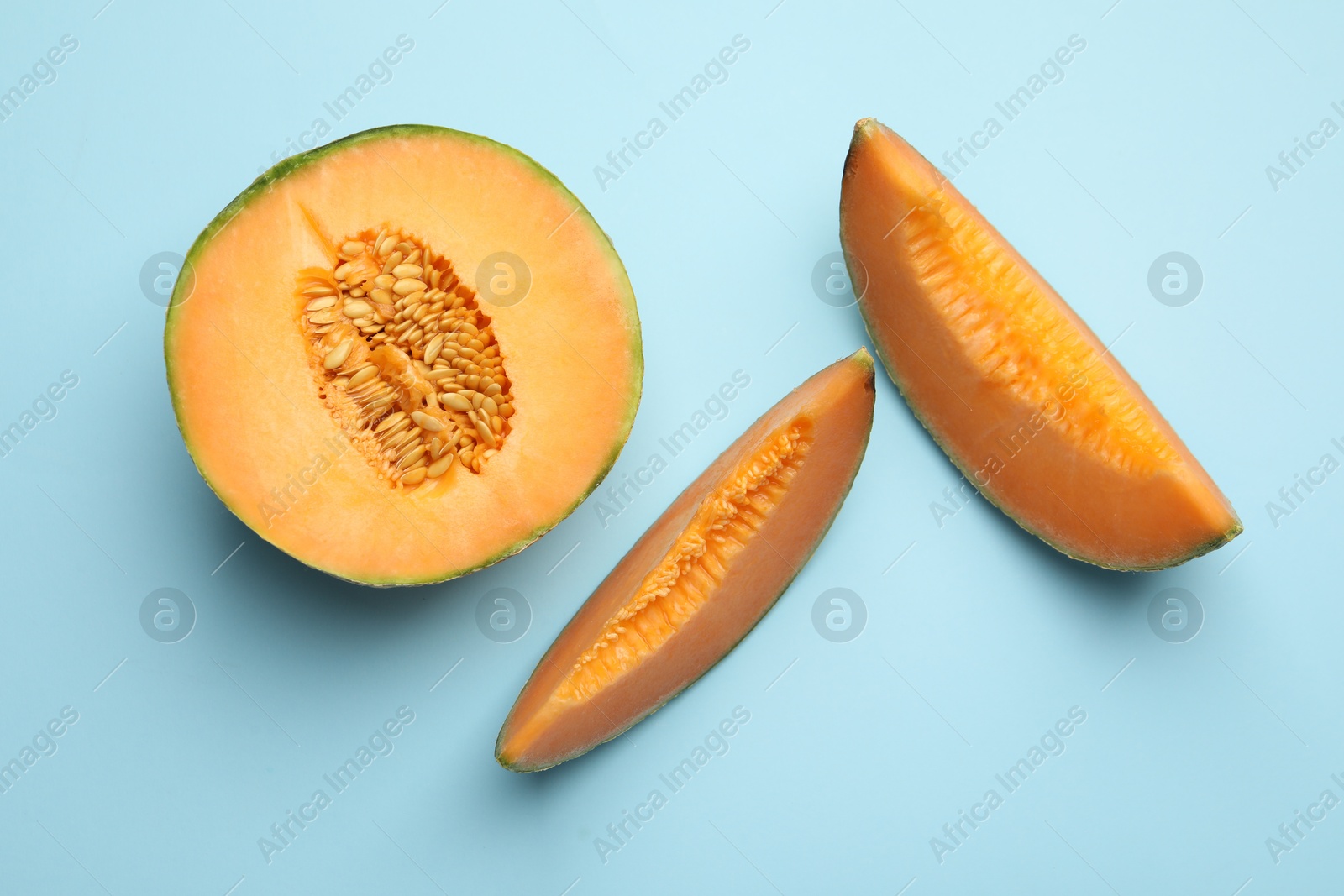 Photo of Pieces of Cantaloupe melon on light blue table, flat lay