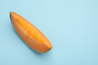 Piece of fresh Cantaloupe melon on light blue table, top view. Space for text