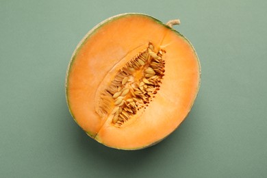 Photo of Half of fresh Cantaloupe melon on green table, top view