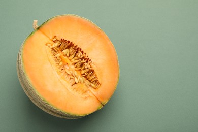 Photo of Half of fresh Cantaloupe melon on green table, top view. Space for text