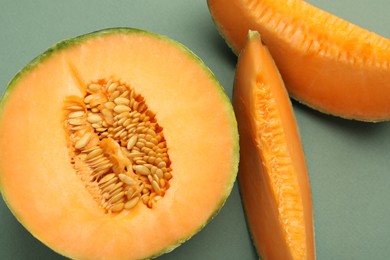 Photo of Pieces of Cantaloupe melon on green table, flat lay