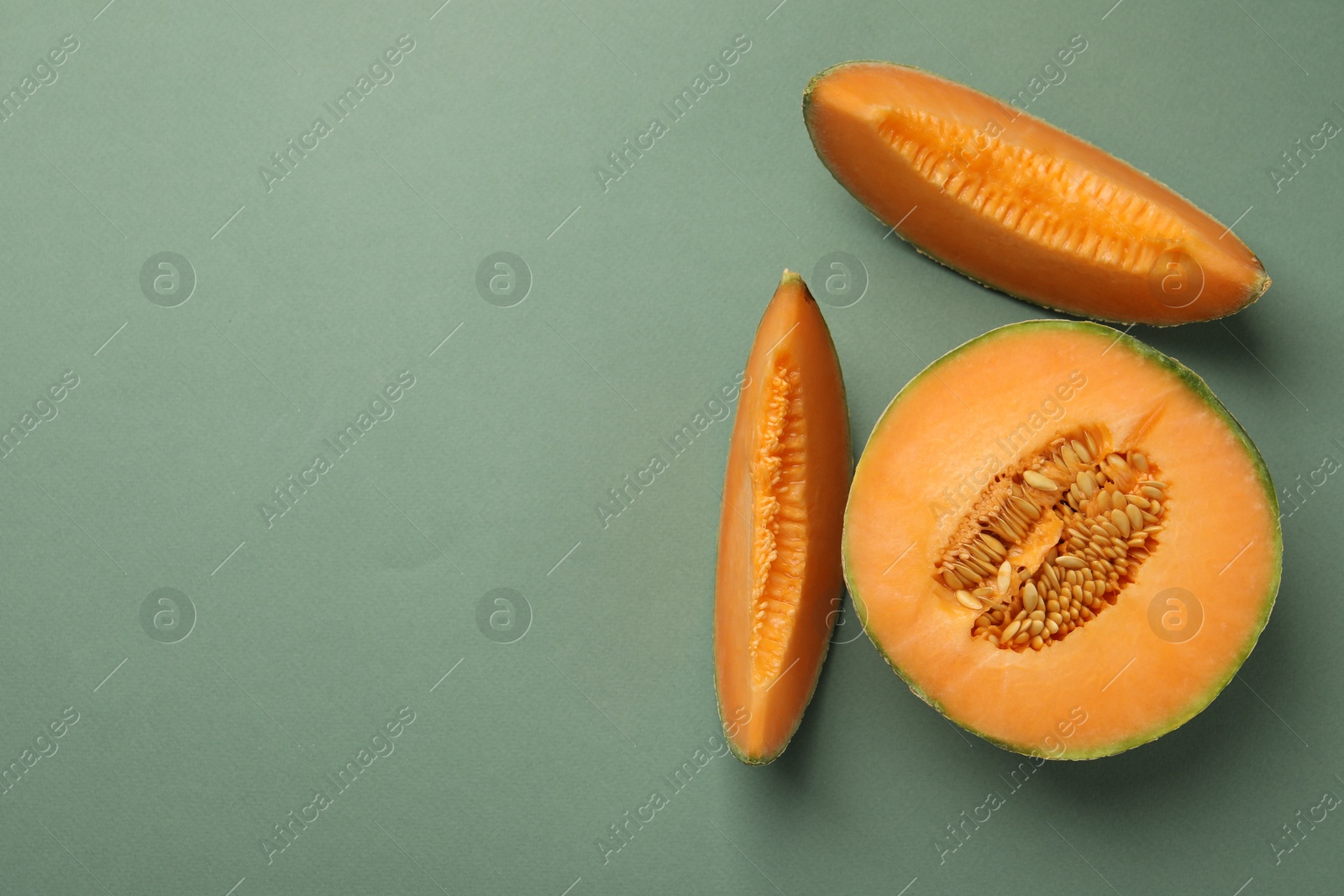 Photo of Pieces of Cantaloupe melon on green table, flat lay. Space for text