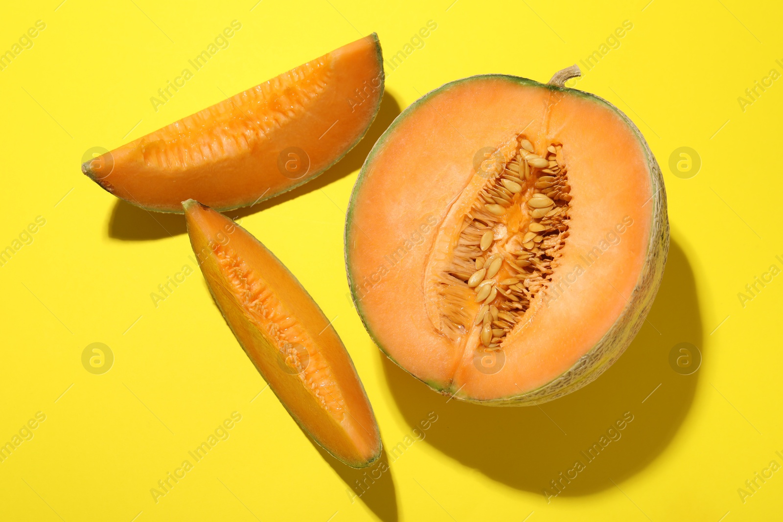 Photo of Pieces of fresh Cantaloupe melon on yellow table, flat lay