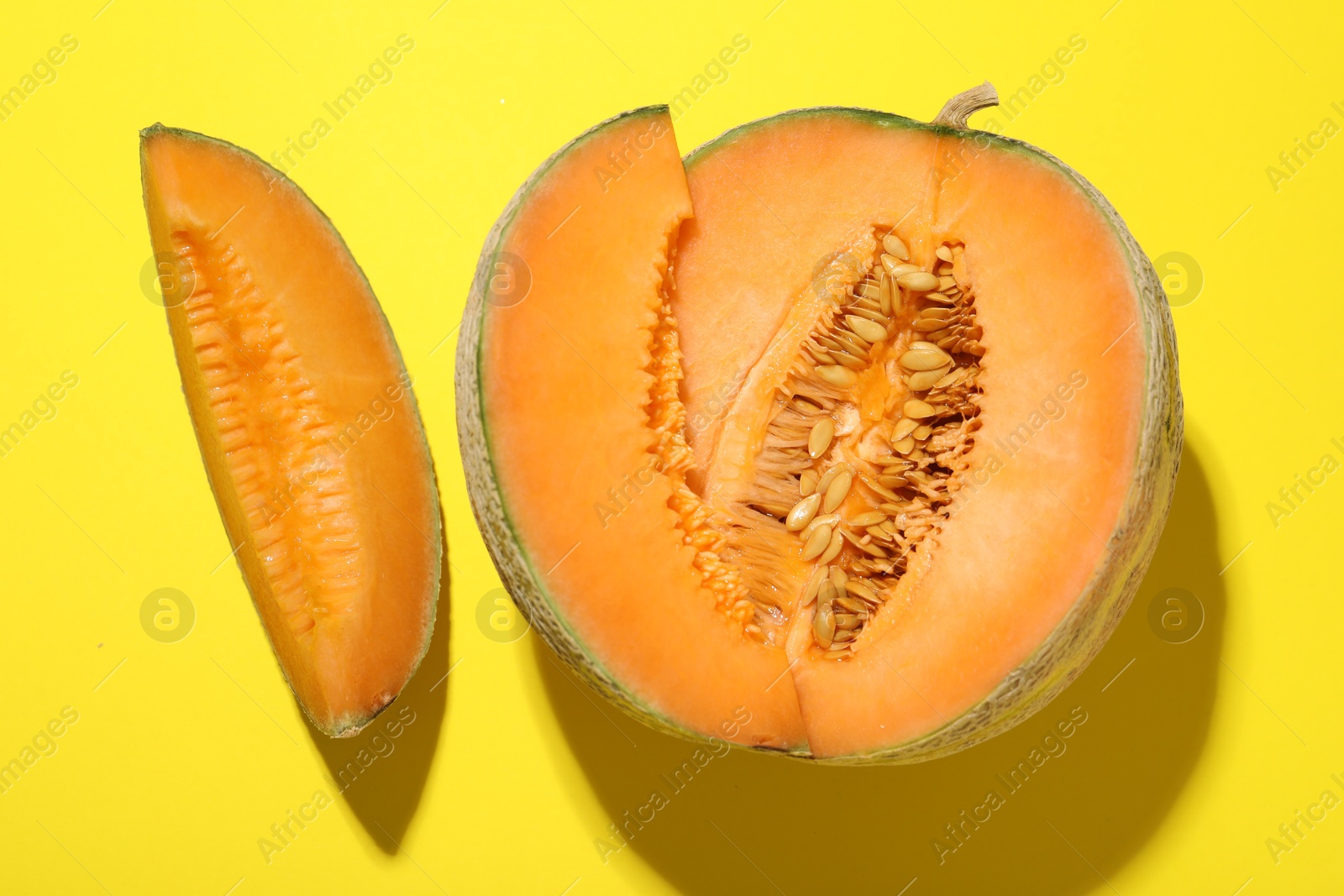 Photo of Pieces of fresh Cantaloupe melon on yellow table, flat lay