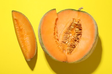 Pieces of fresh Cantaloupe melon on yellow table, flat lay