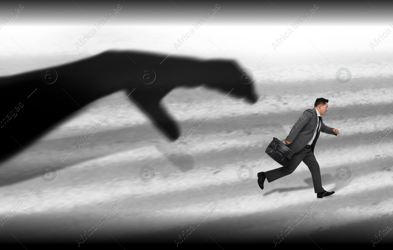 Image of Silhouette of big hand catching running away small businessman on light background. Authority, abuse concepts