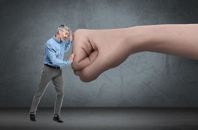 Image of Small businessman pushing away big fist on grey background. Authority, abuse, conflict concepts