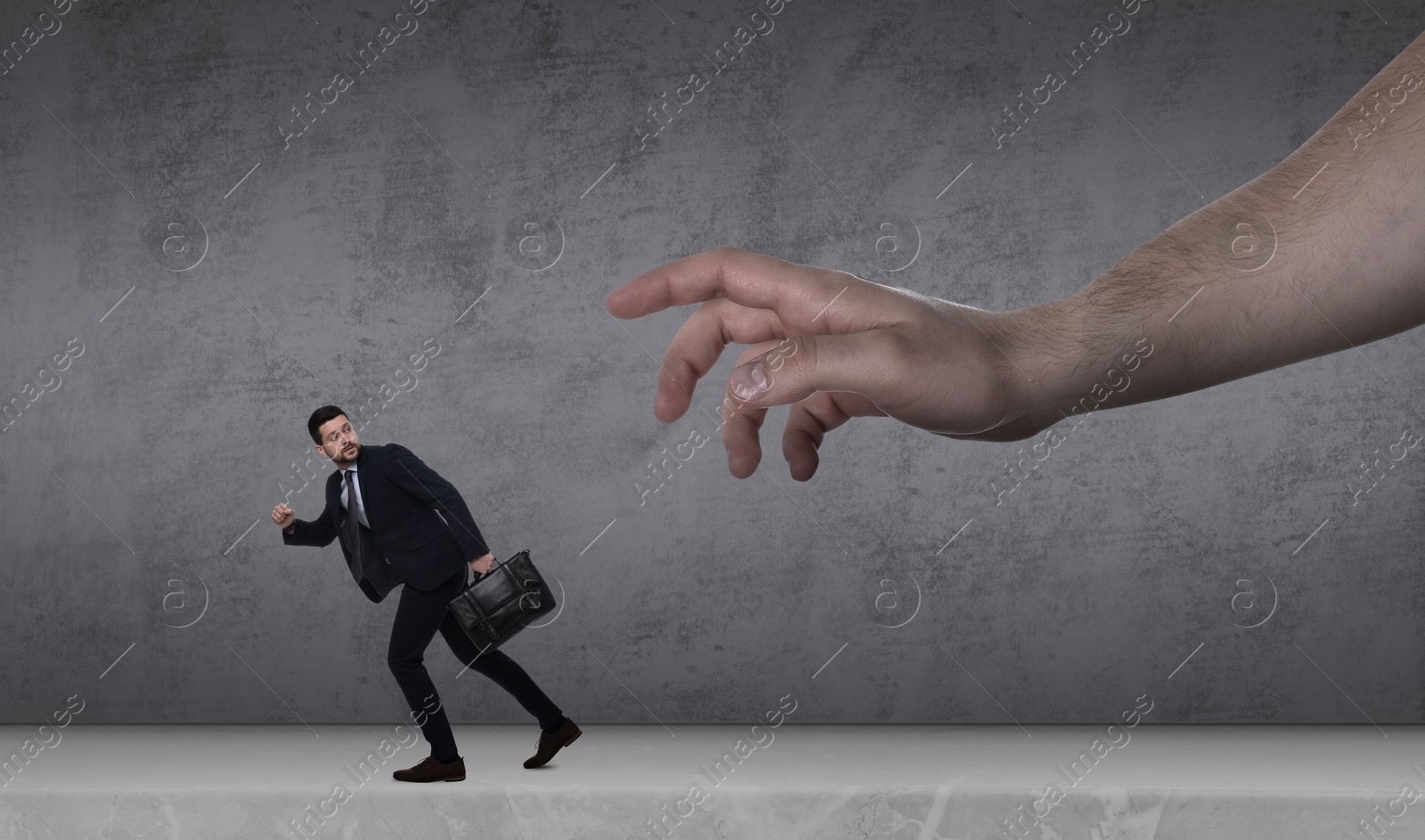 Image of Big hand catching running away small businessman on grey background. Authority, abuse, conflict concepts