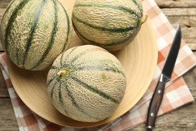 Ripe Cantaloupe melons and knife on wooden table, flat lay