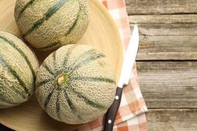 Photo of Ripe Cantaloupe melons and knife on wooden table, flat lay