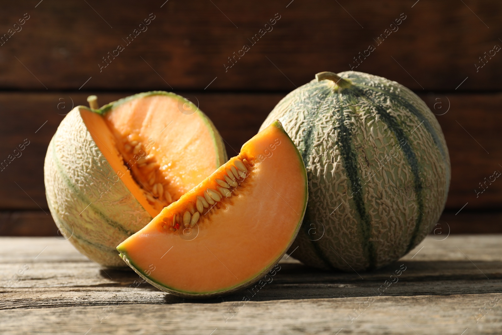 Photo of Whole and cut ripe Cantaloupe melons on wooden table