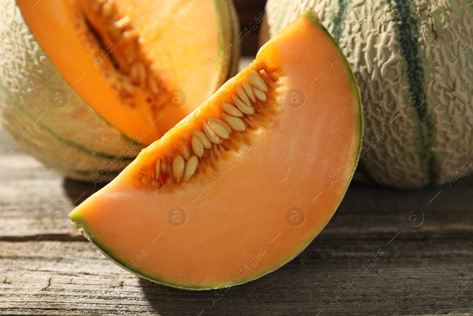 Photo of Whole and cut ripe Cantaloupe melons on wooden table, closeup