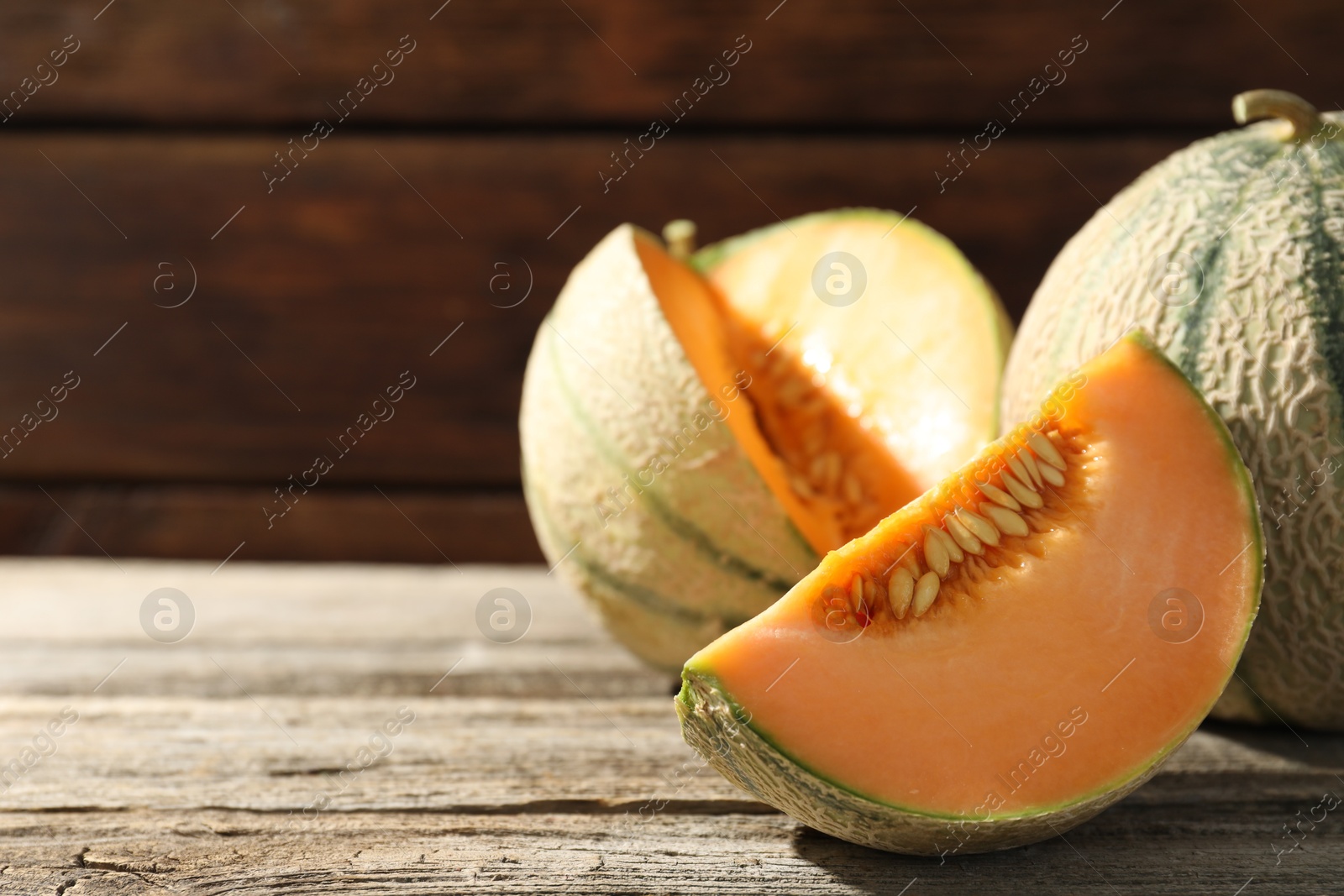 Photo of Whole and cut ripe Cantaloupe melons on wooden table, closeup. Space for text