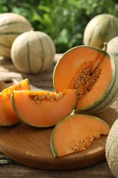 Tasty ripe Cantaloupe melons on wooden table outdoors, closeup