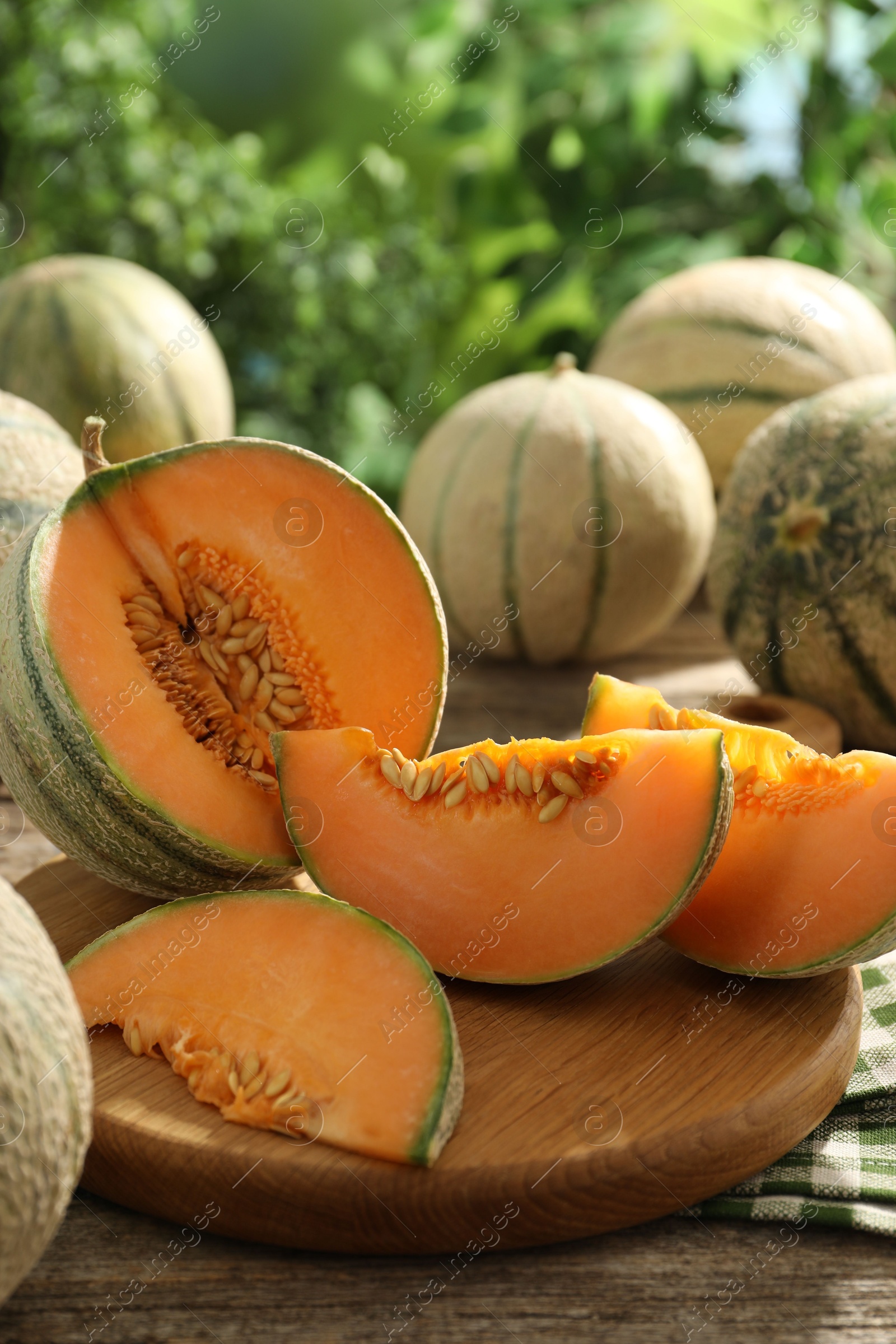 Photo of Tasty ripe Cantaloupe melons on wooden table outdoors, closeup