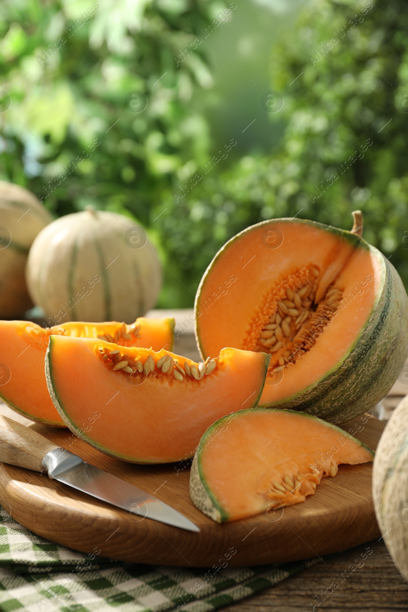 Photo of Cut ripe Cantaloupe melon on wooden table outdoors