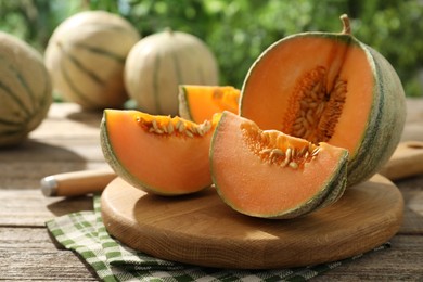 Photo of Cut ripe Cantaloupe melon on wooden table outdoors, closeup