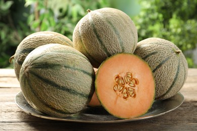 Photo of Whole and cut ripe Cantaloupe melons on wooden table outdoors, closeup