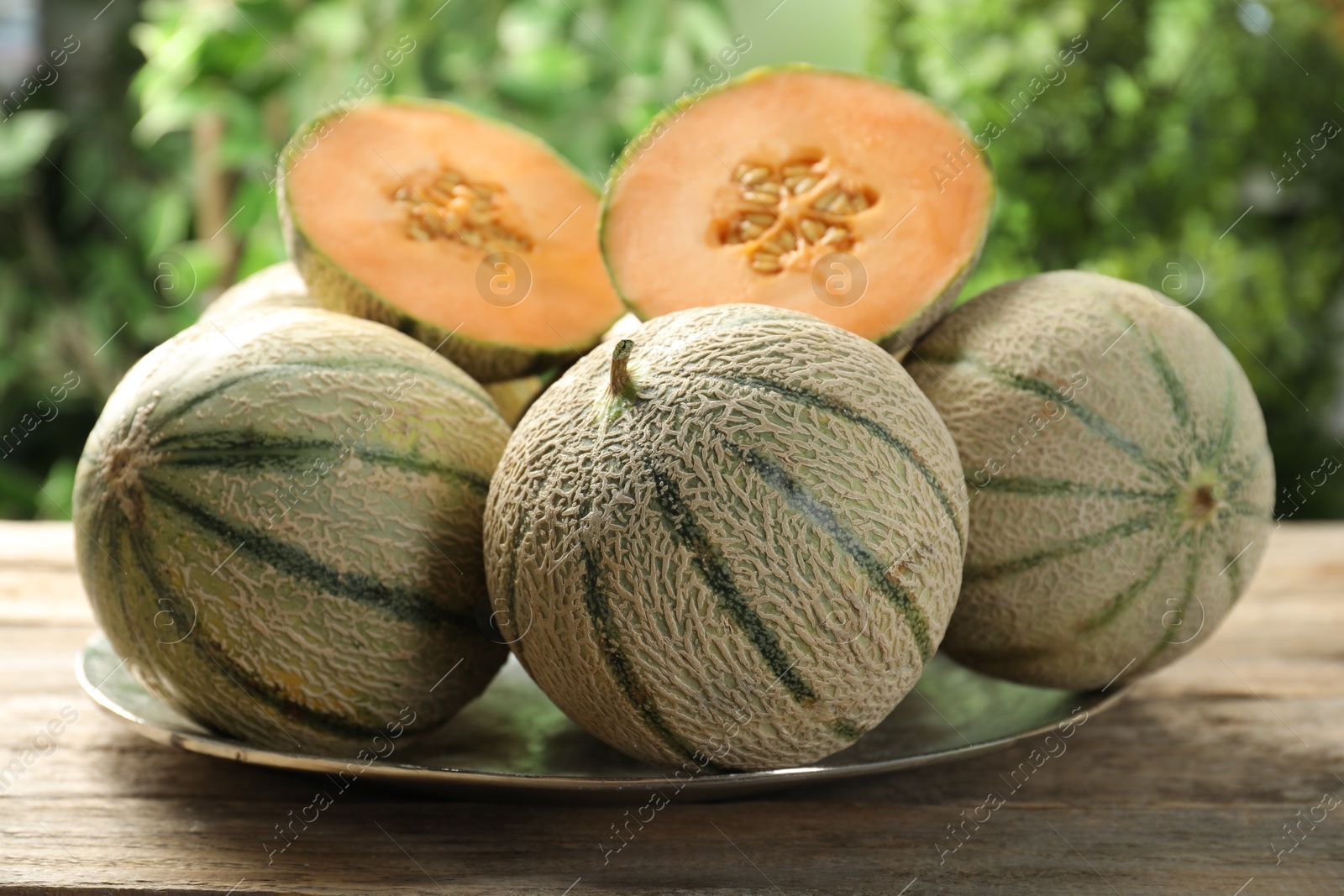 Photo of Whole and cut ripe Cantaloupe melons on wooden table outdoors, closeup