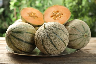 Photo of Whole and cut ripe Cantaloupe melons on wooden table outdoors, closeup