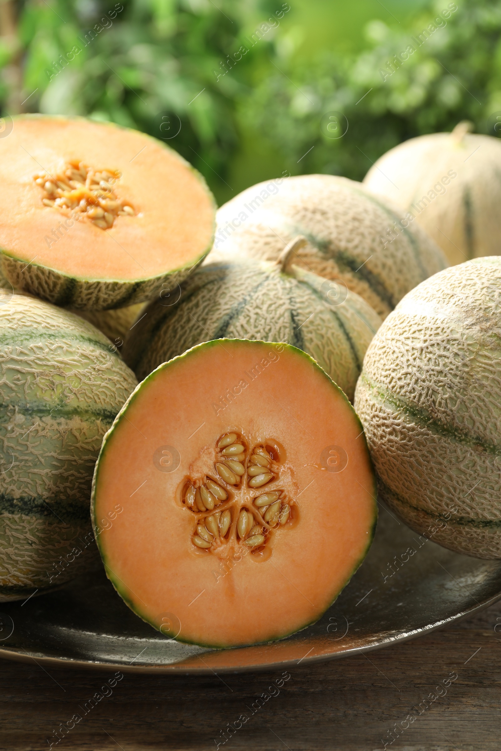 Photo of Whole and cut ripe Cantaloupe melons on wooden table outdoors, closeup