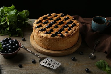 Homemade blueberry pie, fresh berries, cake server and mint on wooden table