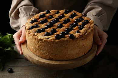 Photo of Woman with homemade blueberry pie at wooden table, closeup