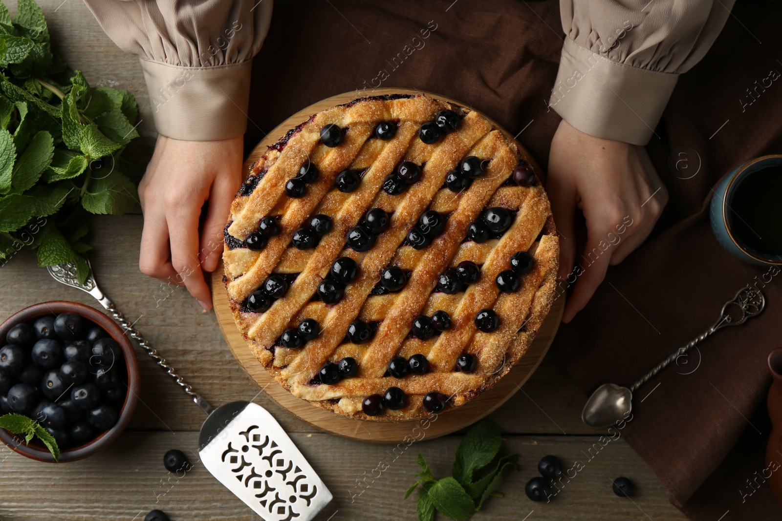 Photo of Woman with homemade blueberry pie at wooden table, top view