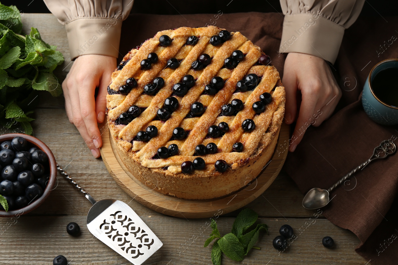 Photo of Woman with homemade blueberry pie at wooden table, closeup