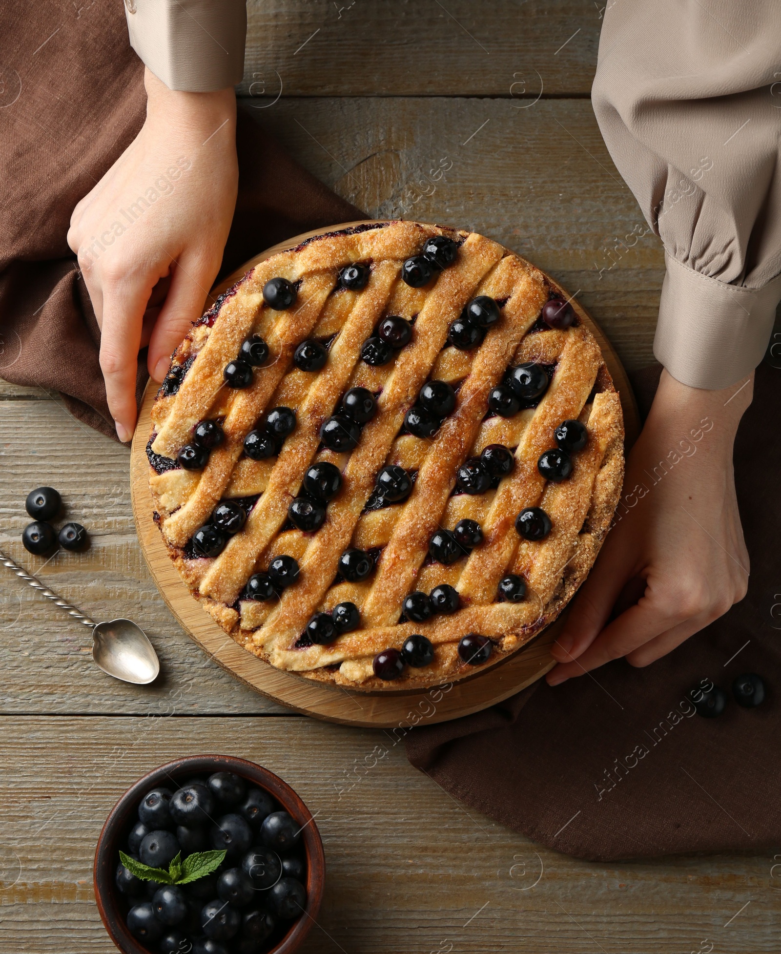 Photo of Woman with homemade blueberry pie at wooden table, top view