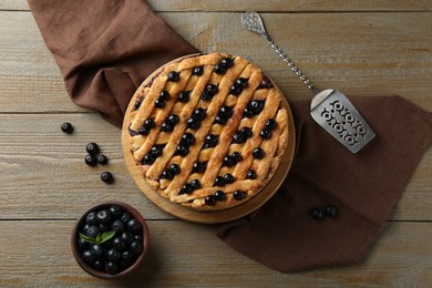 Photo of Homemade blueberry pie, cake server and fresh berries on wooden table, flat lay