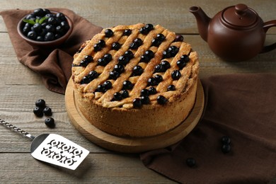 Homemade blueberry pie, cake server and fresh berries on wooden table