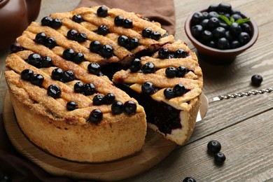 Photo of Taking slice of homemade blueberry pie and fresh berries on wooden table, closeup