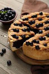 Photo of Taking slice of homemade blueberry pie and fresh berries on wooden table, closeup