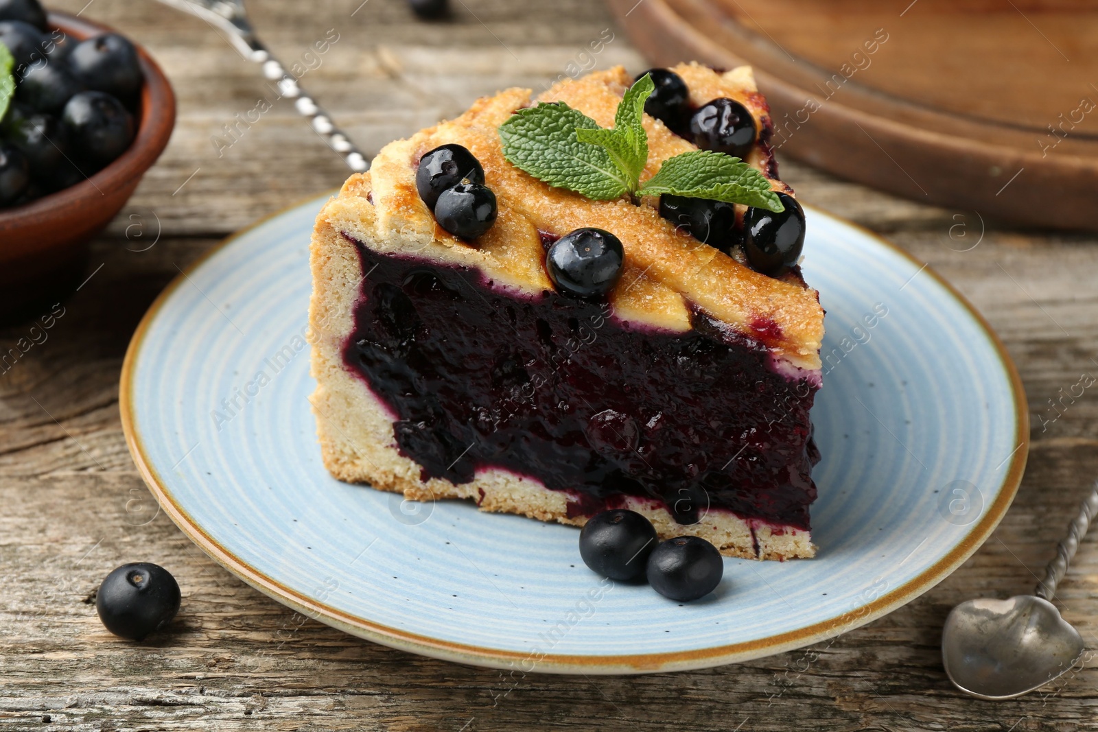 Photo of Slice of homemade blueberry pie on wooden table, closeup