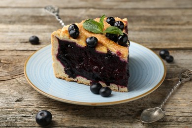 Photo of Slice of homemade blueberry pie on wooden table, closeup