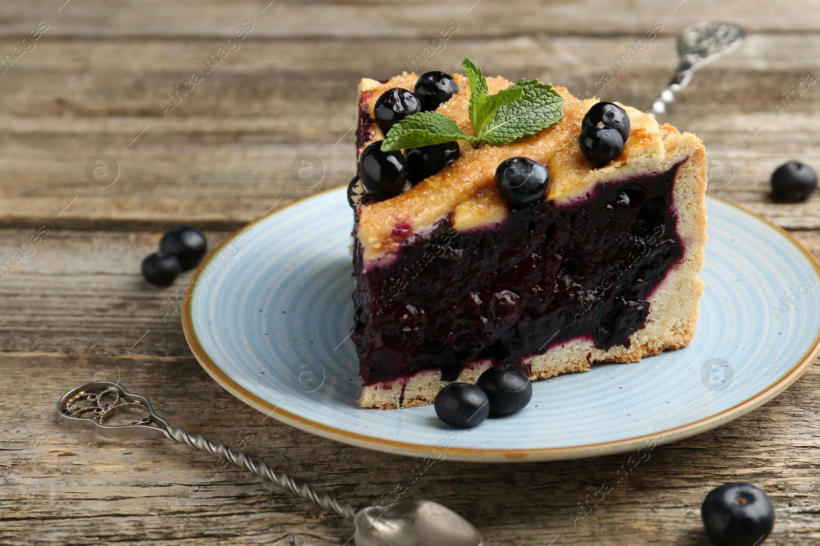 Photo of Slice of homemade blueberry pie on wooden table, closeup