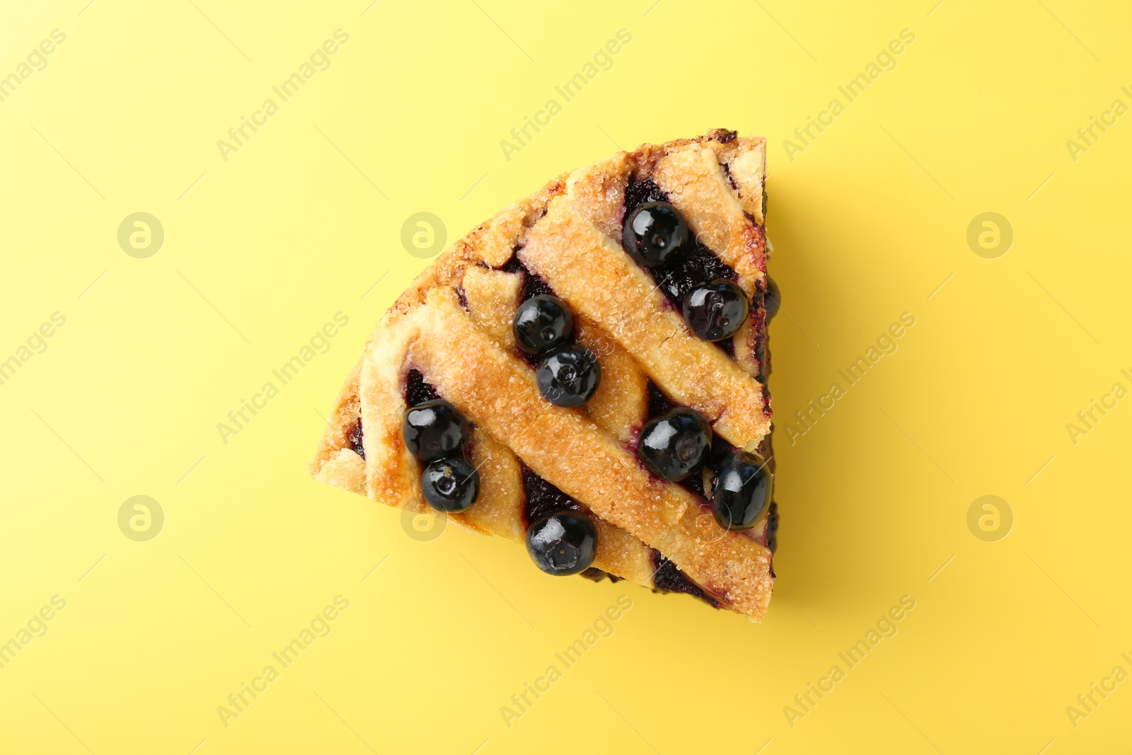 Photo of Slice of homemade blueberry pie on yellow background, top view