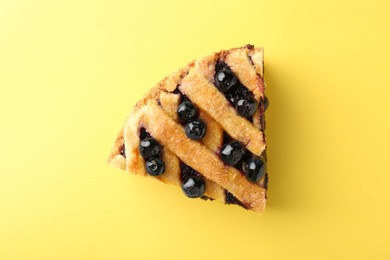 Photo of Slice of homemade blueberry pie on yellow background, top view