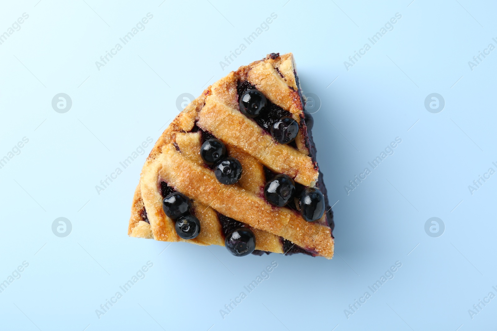 Photo of Slice of homemade blueberry pie on light blue background, top view