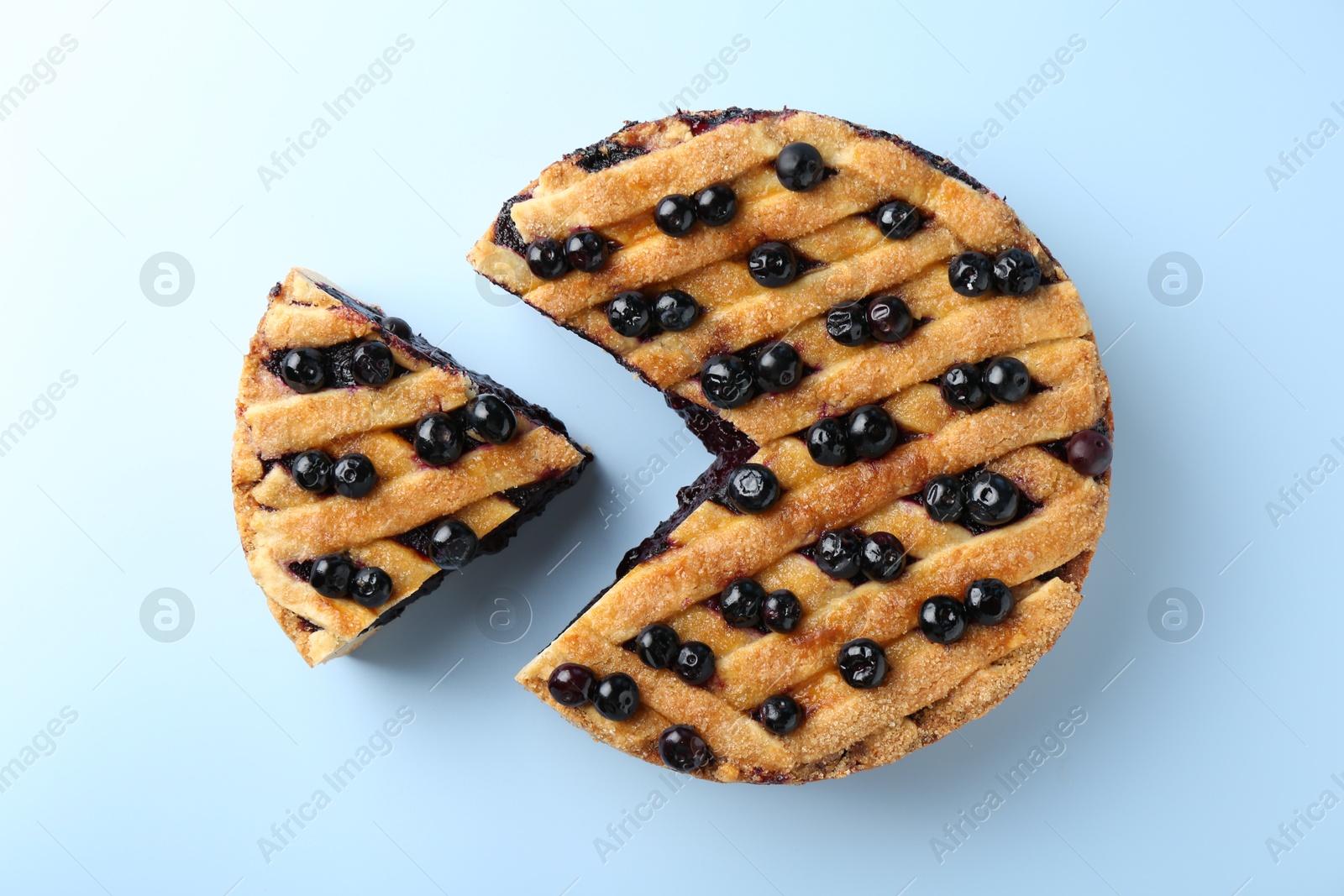 Photo of Cut homemade blueberry pie on light blue background, top view