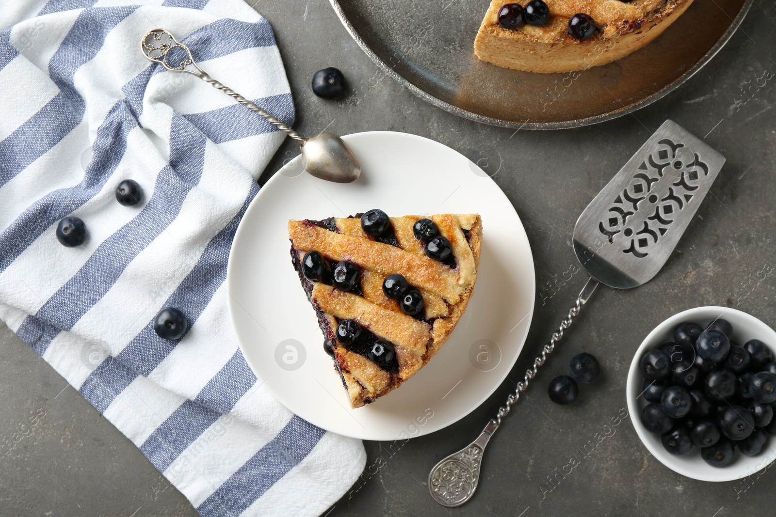 Photo of Slice of delicious homemade blueberry pie served on grey table, flat lay