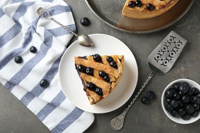 Photo of Slice of delicious homemade blueberry pie served on grey table, flat lay