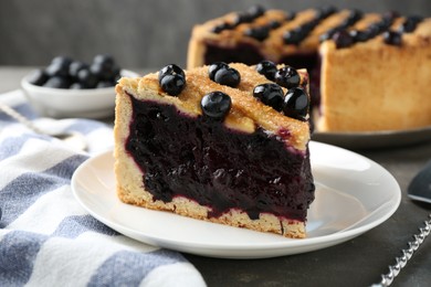 Photo of Slice of delicious homemade blueberry pie served on grey table, closeup