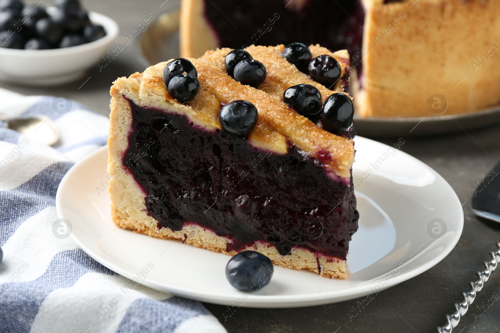 Photo of Slice of delicious homemade blueberry pie served on grey table, closeup