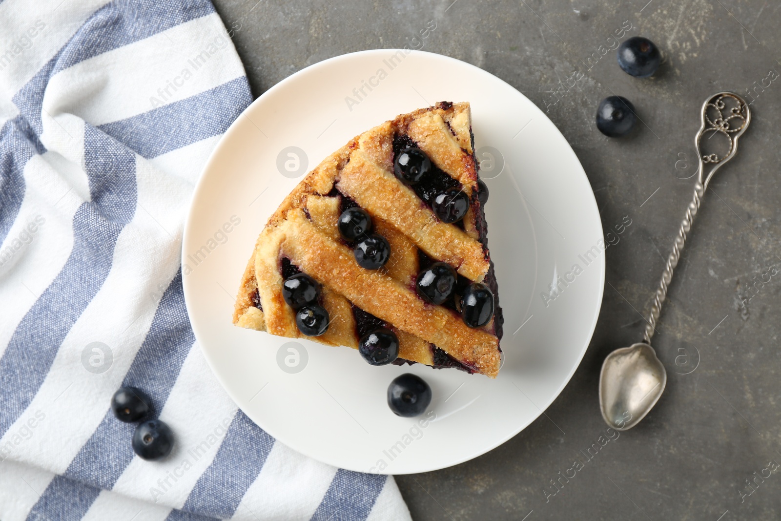 Photo of Slice of delicious homemade blueberry pie served on grey table, flat lay